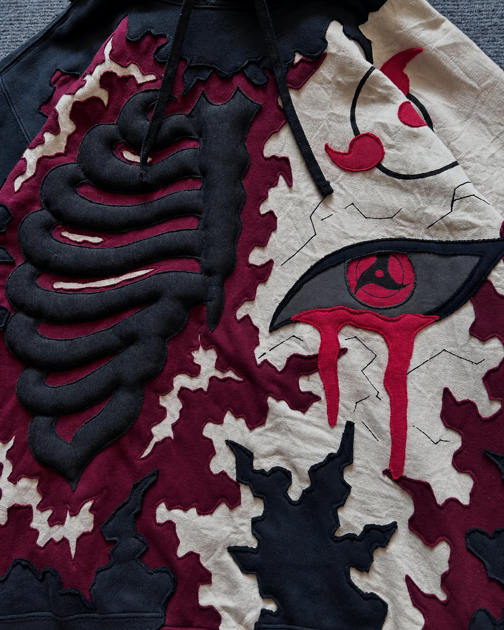 Close-up of Noctra Crimson Eclipse Hoodie featuring layered appliqué, embroidery and 3D skeletal detailing